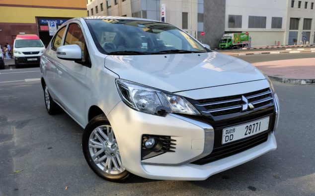 A grey Mitsubishi Attrage 2025 sedan parked in Dubai, featuring a compact fuel-efficient design, 1.2L petrol engine with automatic CVT transmission, spacious interior, and modern safety features, ideal for affordable sedan car rental in Dubai.